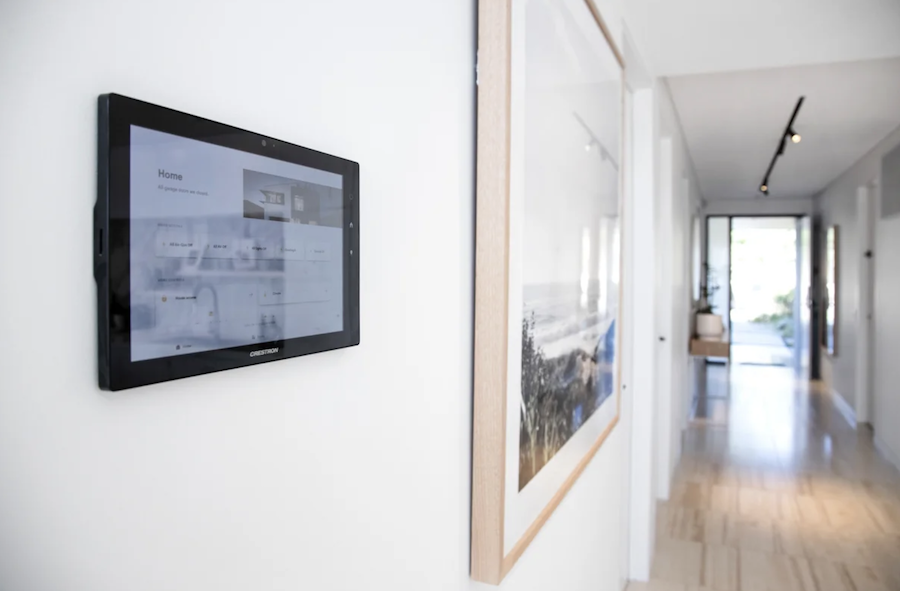 A hallway in a Sydney home with a smart home tablet mounted on the wall. 