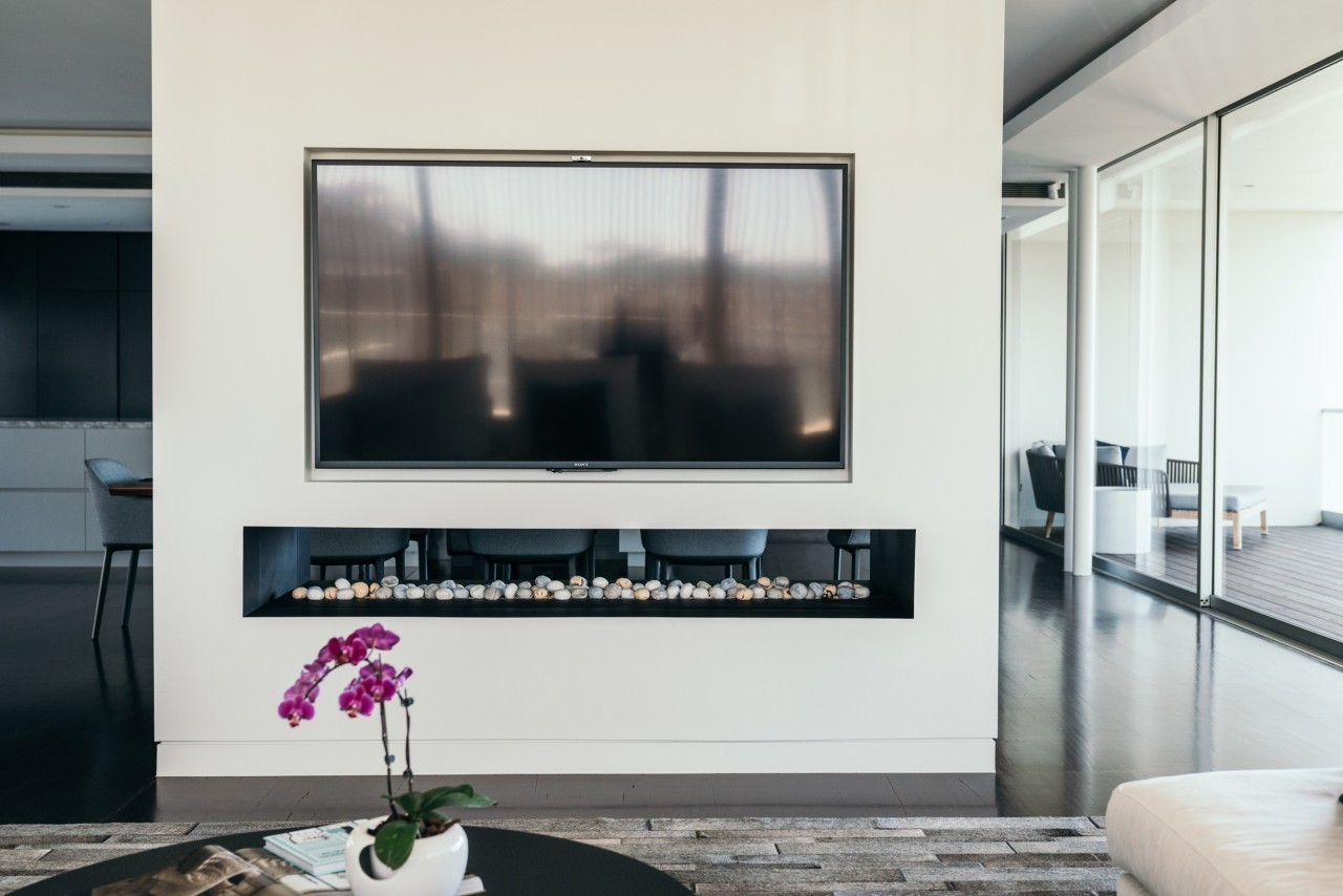 Luxury media room with a display installed above a fireplace. 