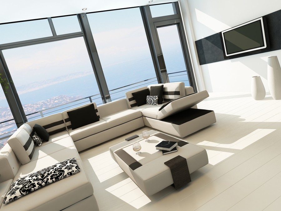 An open living space featuring a media setup with a mounted TV and large windows with the view of the bay.