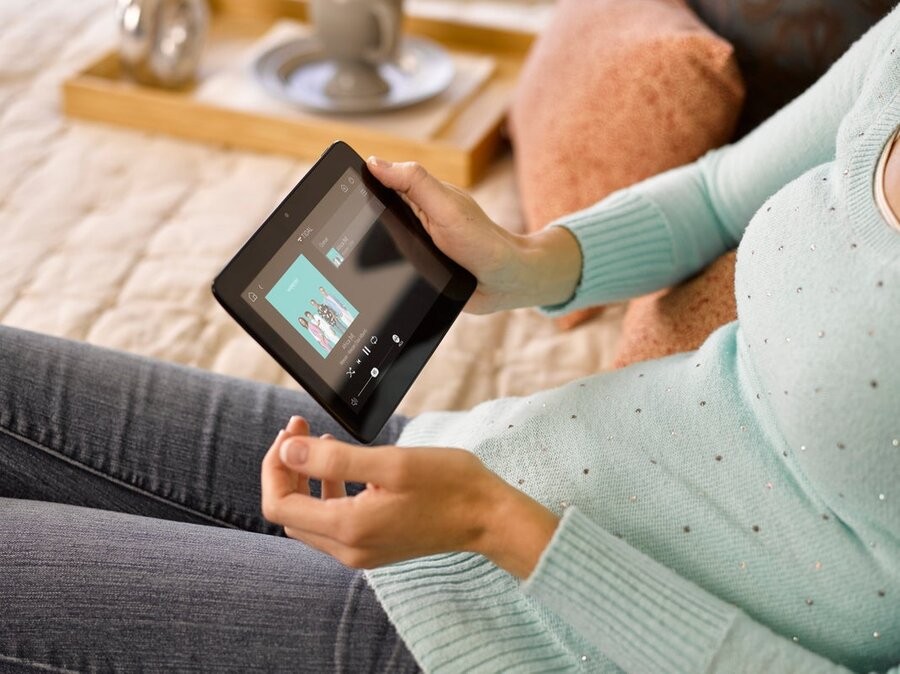 A woman using a touchscreen tablet to play music from her Control4 system.